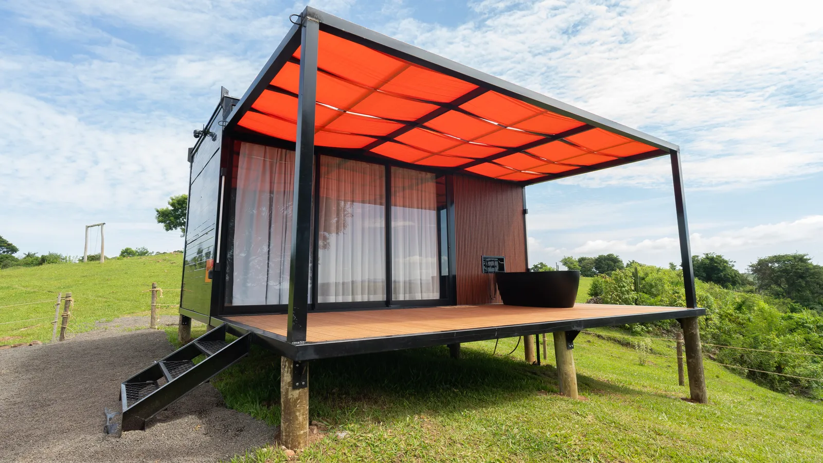 Cabana Mumajo com pergolado laranja e deck, aberta para o vale