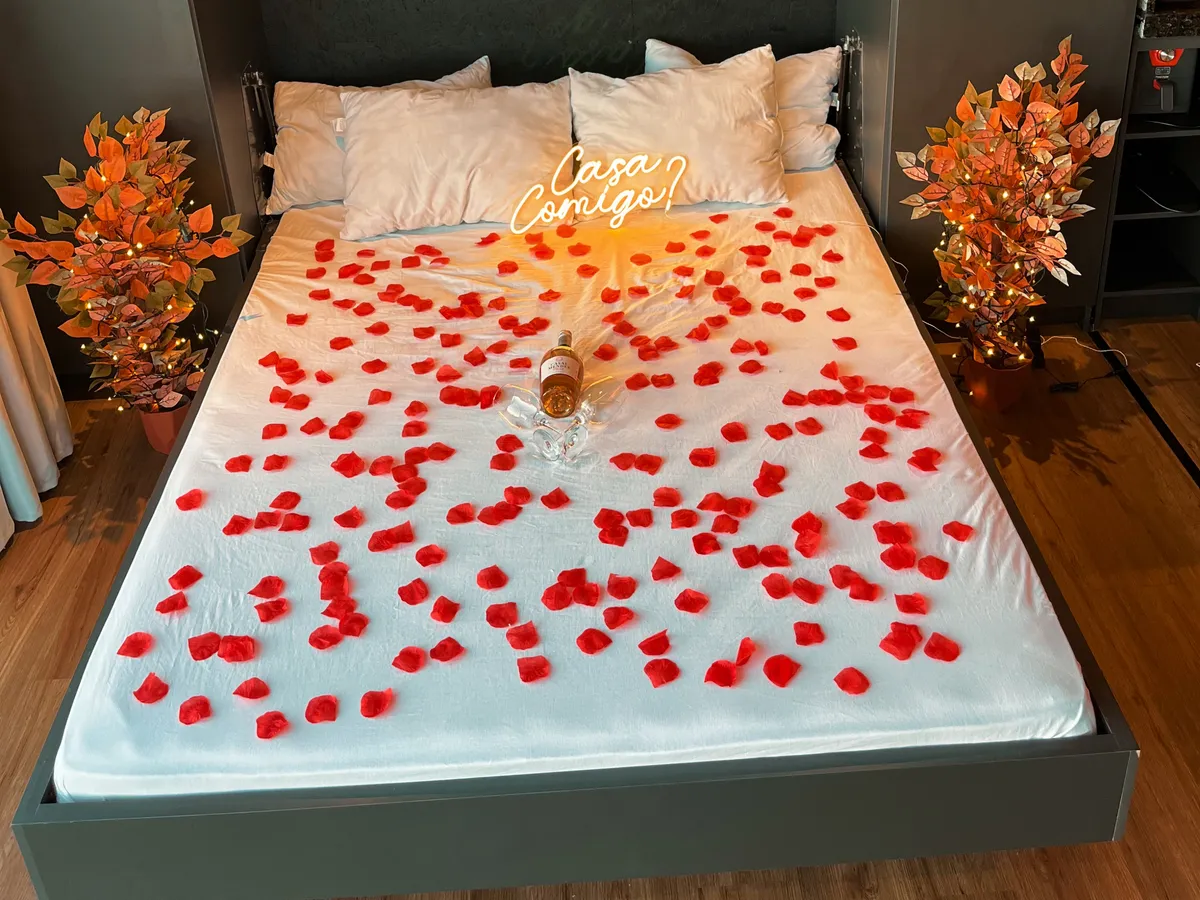 Cama preparada com pétalas e letreiro Casa comigo