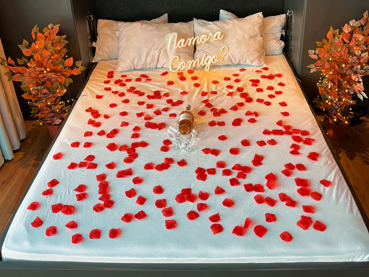 Cama preparada com pétalas e letreiro Namora comigo