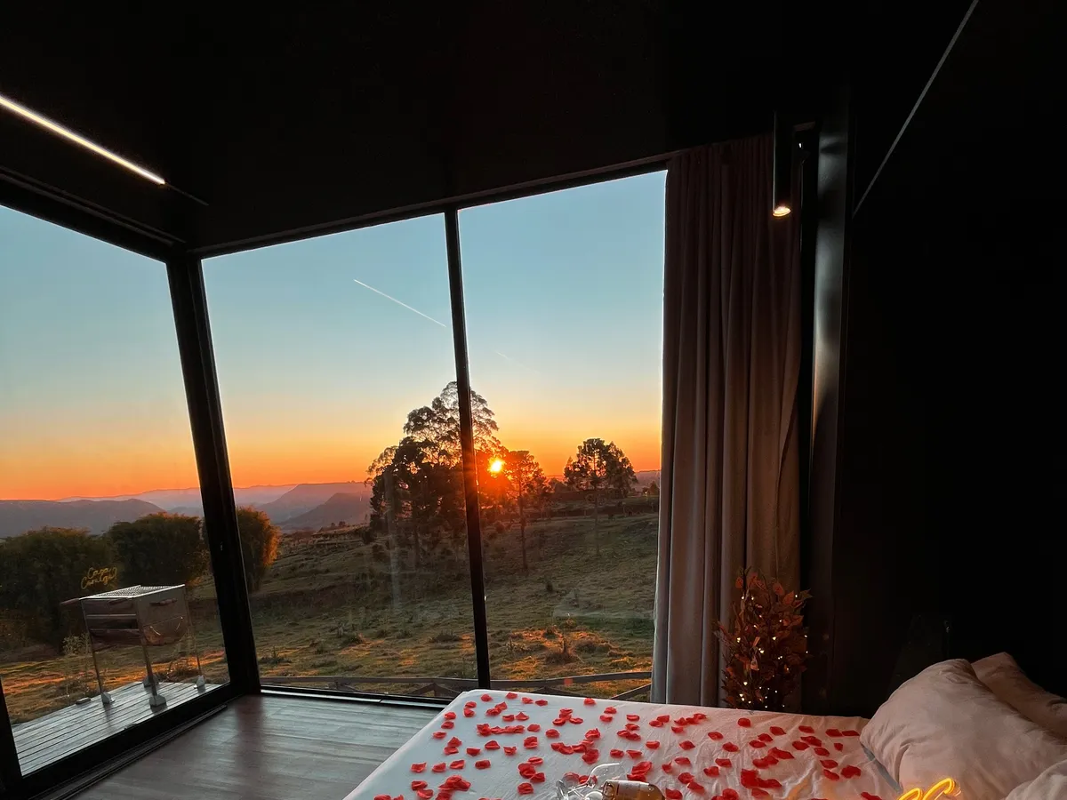 Pôr do sol visto da cabana, com pétalas na cama